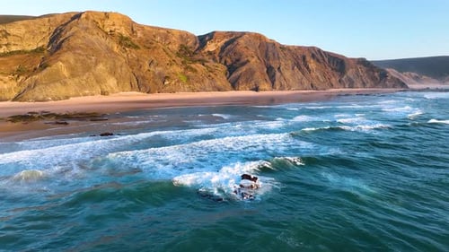 Cliff-lined beach with rolling surf waves
