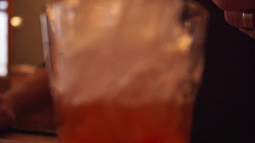 Barkeeper gießt rotes Cocktailgetränk auf Glas mit zerstoßenem Eis ein. - Nahaufnahme, verkleinern