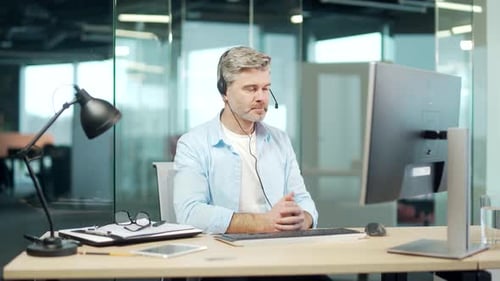 Man Wearing Headset Talking at Computer in Office
