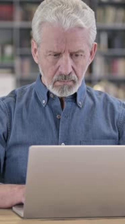 Senior Man Working on Laptop Computer Indoors