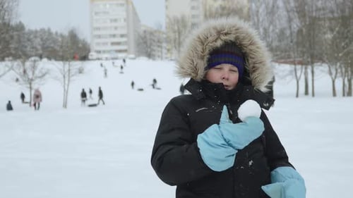 Portrait of Child Throwing Snowball in Mittens in City