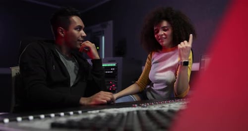 Two People Work at Mixing Board in Studio