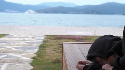 Youthful Pair Resting on Bench Overlooking Ocean