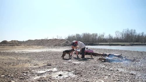 Family on picnic near the river with their dog roasting sausages