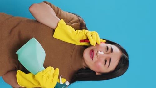 Woman Talks on Phone With Cleaning Supplies