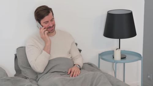 Man in Bed Talking on Mobile Phone