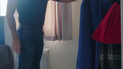 Man Hanging Plaid Shirt in Bedroom