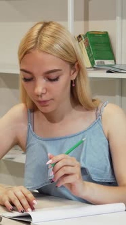 Focused Female Student Diligently Completing Her Homework on a Laptop