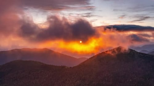 Golden Sunrise Above Forested Mountains with Colorful Clouds