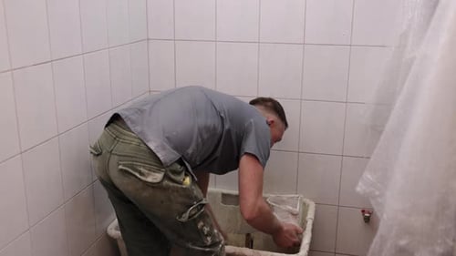 Man Scrubbing in White Tiled Room