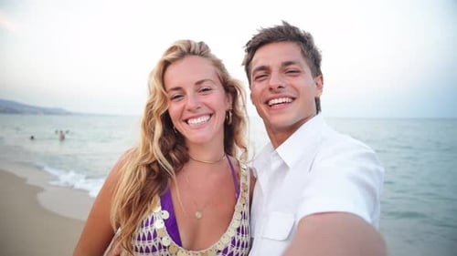 Happy Couple Enjoying a Fun Beach Vacation While Taking a Selfie Near the Beautiful Coastline at