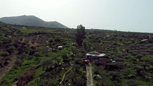 Aerial descending shot showing family in old allotment garden surrounded by farm fields with cultiva