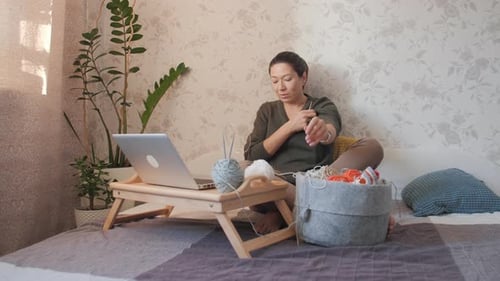 Woman Knitting and Using Laptop at Home