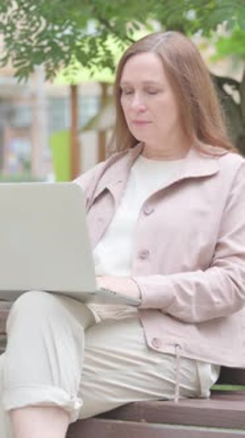 Woman Uses Laptop While Sitting on Park Bench