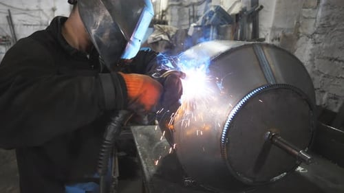 Arbeiter beim Schweißen von Schutzmasken, Schweißer von Metallkonstruktionen, die Verbindung zwischen zwei Stahlteilen herstellen