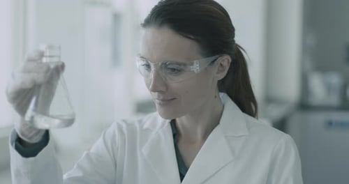 Woman Scientist Examining Liquid in Beaker in Lab