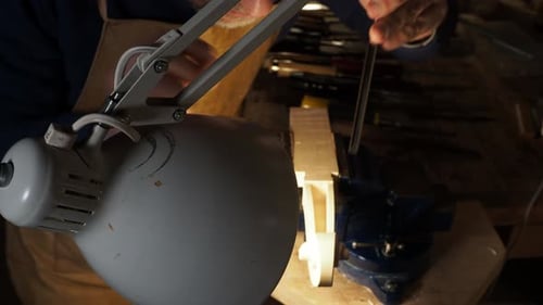 Man Crafting a Violin in Workshop with Hand Tools