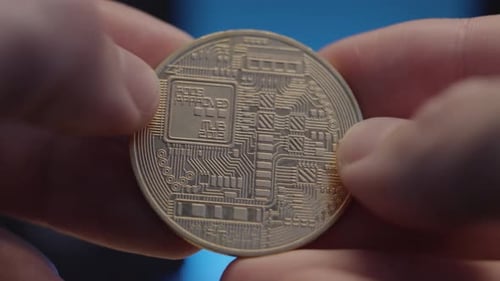 Golden Bitcoin coin close up spinning around fingers , feeling the details of the coin.