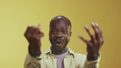 An Energized Man in Casual Attire Raising Fists Amid Cheering and Laughter in Vibrant Studio Setting