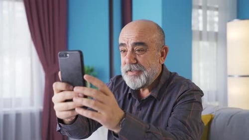 Senior Man Video Calling with Smartphone Indoors