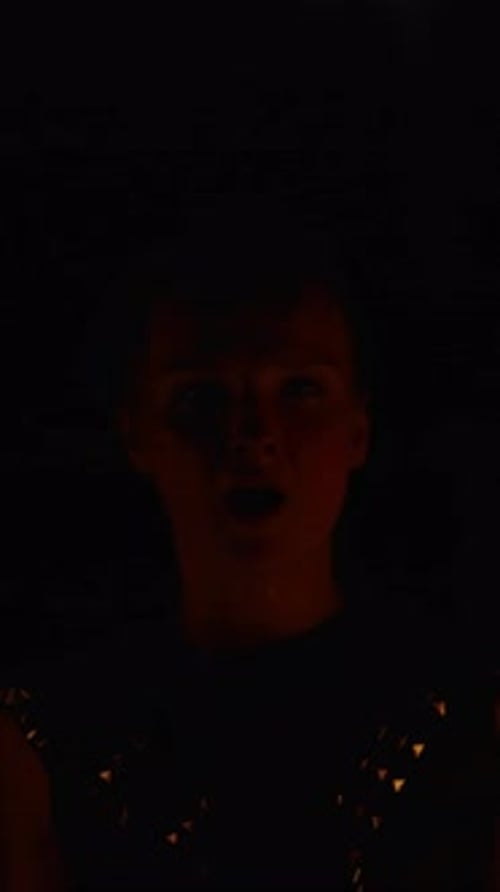 Silhouette levant un bras dans l'obscurité presque totale avec une faible lumière chaude éclairant subtilement