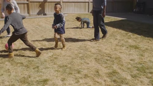 Family fun playing football together in the backyard on a sunny Canada day