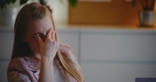 Woman Rubs Face While Sitting in Office