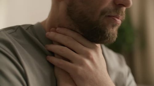 Close Up of Man Holding Neck while Experiencing Sore Throat