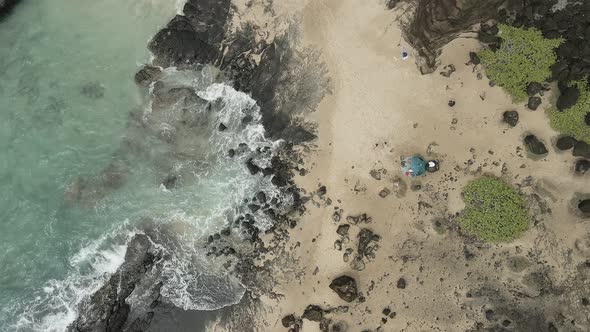 Aerial overview of swimmers in a secluded beach cove tracking forward ...