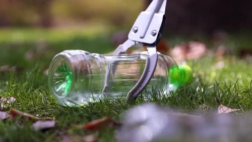 Picking Up Litter in Green Grass with Tongs