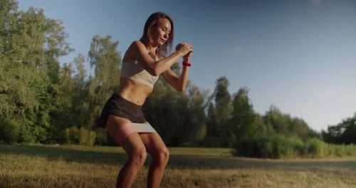 Woman Exercising With Band Outdoors on Sunny Day