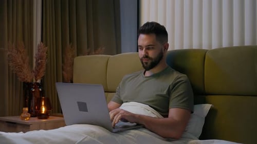 Man Working on Laptop in Bed at Night