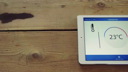 Tablet showing temperature app on a wooden table