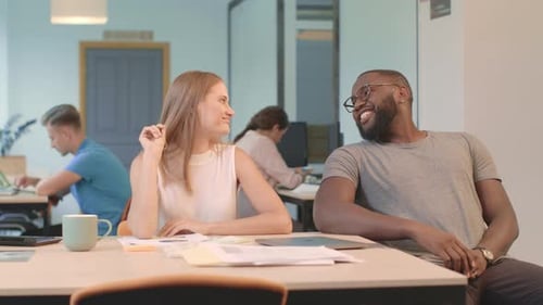 Young Man Rolling Up to Lady Sitting on Chair in Office. African