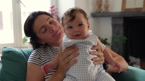 Mother holding baby, smiling affectionately, joyful moment, parent-child connection, warmth, love,