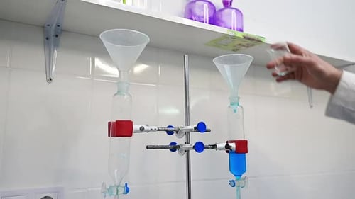 Scientist pours blue liquid into reservoir. Liquid goes to the glass tube right onto the diaper.