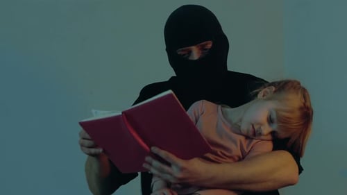 Kidnapper in a Black Balaclava Holding a Child in His Arms Using Book and Reading Little Girl
