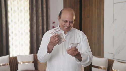 Mature Man Counting Money Indoors
