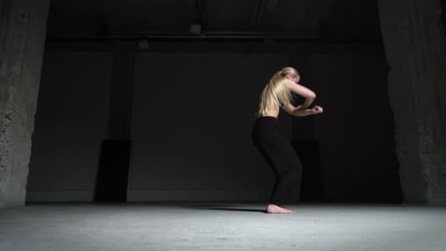 Energetic Young Woman Choreographer Dancing Alone in Studio with Concrete Walls