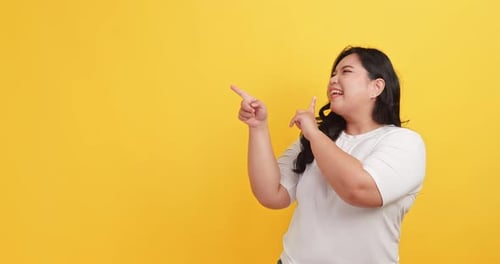 Enthusiastic Woman Points Up Against Yellow Backdrop