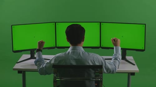 Man Celebrating And Dancing While Working With Mock Up Multiple Computer Monitor In Green Screen