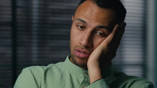 Sad Young Man Resting Head in Hand Indoors
