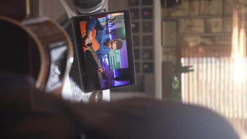 Person with Guitar Watching Guitarist on Laptop