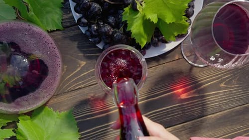 Rotwein, der während eines romantischen Dates in Kristallglas gegossen wird, frische Traubenbüschel