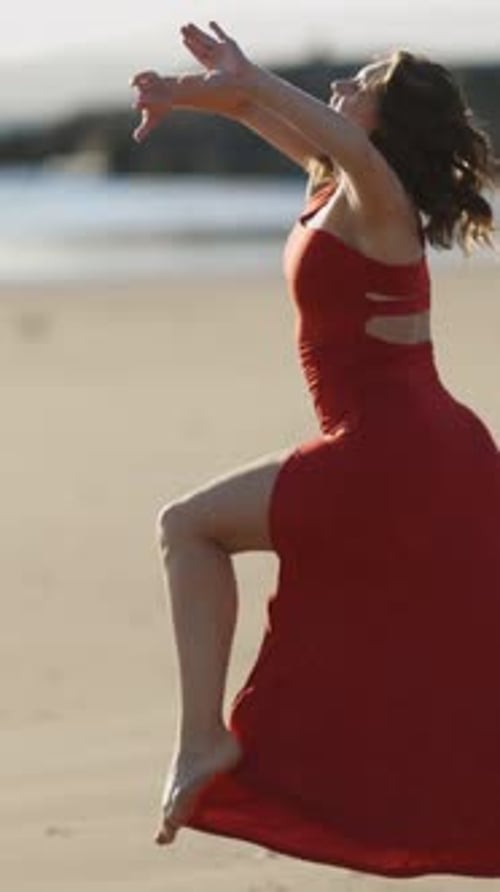 Woman in Red Dress Dancing on the Beach
