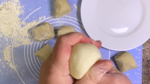 Forming round balls from raw dough for further rolling with a rolling pin. Top view.