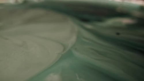 Extreme close up of a dark grey liquid moving to the right side of the frame. Liquid looking like a