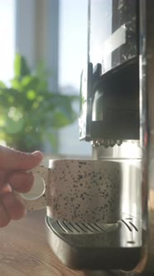 Filling Spotted Mug with Coffee From Machine Indoors