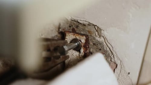 Bolt with Washer is Screwed Into Old Mount Using Pliers Closeup