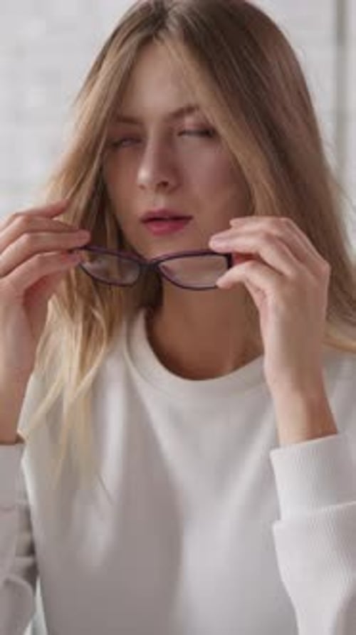 Woman Takes Off Glasses Against Card Index